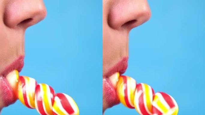 垂直特写，女性性感的嘴唇用红色唇膏吮吸大螺旋长方形糖果棒棒糖。复制空间。蓝色背景