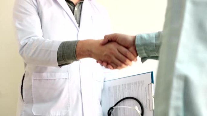 医生和病人祝贺在医院办公室前握手。