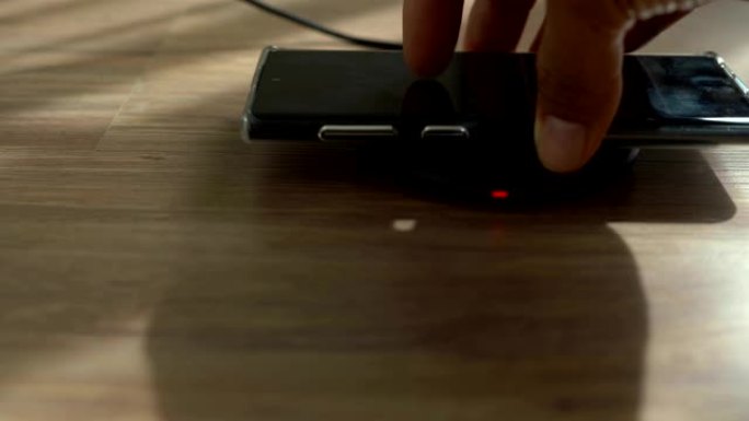 桌子上的无线充电器上正在充电的智能手机电池的特写