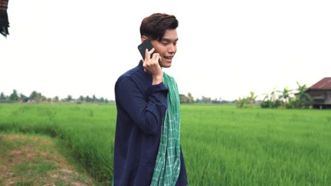 一名男子在稻田前用电话交谈和自拍