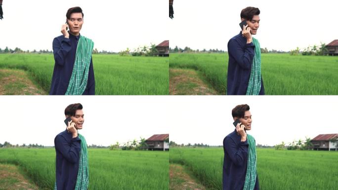 一名男子在稻田前用电话交谈和自拍