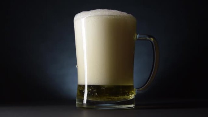 啤酒滴从溢出的啤酒杯的侧面流下。慢动作和黑暗风格