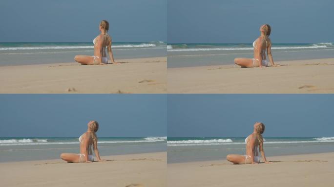 女士弯曲的膝盖坐在沙滩上，看着晴朗的天空