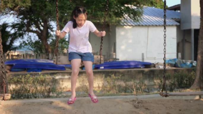 亚洲女孩在秋千上玩耍，在公园里玩得开心。