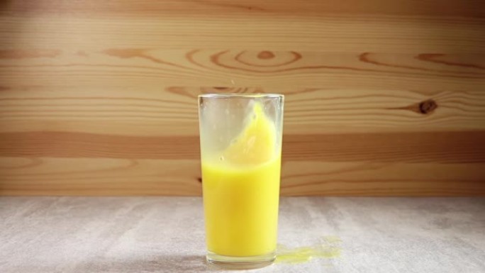 冰块滴在装有橙汁的玻璃杯中。慢动作