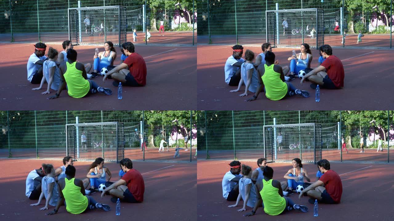 年轻的男女朋友坐在足球场上聊天