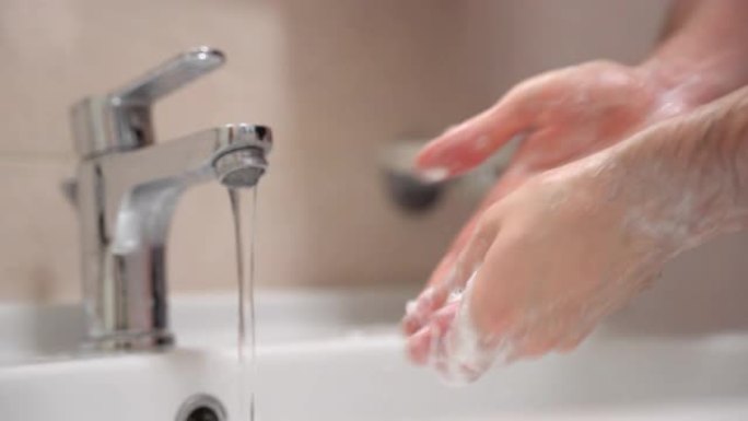 流动的温水从水龙头和人小心地洗手与泡沫肥皂，去除脏污，微生物和细菌。每个人的日常义务卫生，护肤和健康