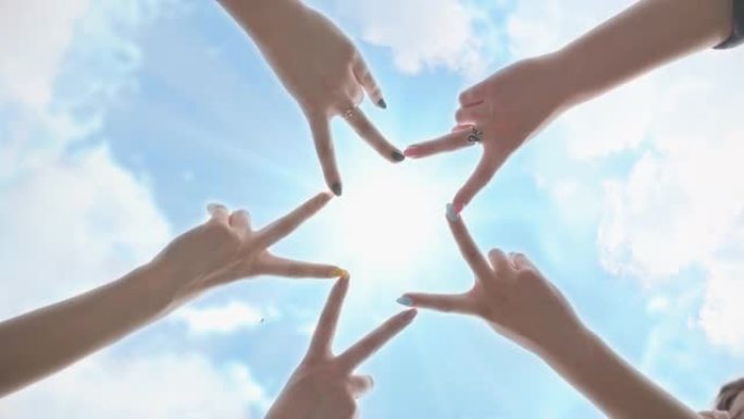 人们用手指在阳光照耀的蓝天下形成恒星形状