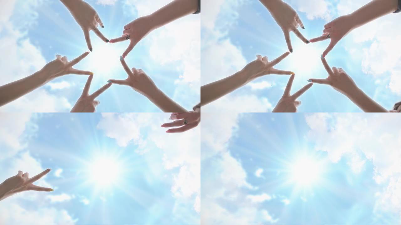 人们用手指在阳光照耀的蓝天下形成恒星形状