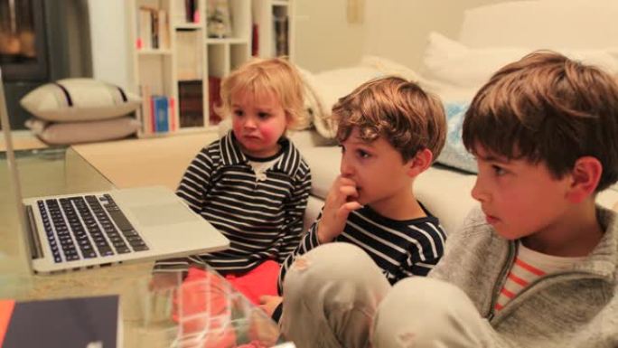 孩子们在沙发旁在家中的笔记本电脑上观看在线内容。孩子们在屏幕上主演
