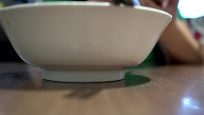 母亲在一家亚洲餐厅使用手机。专注于用筷子的空碗。