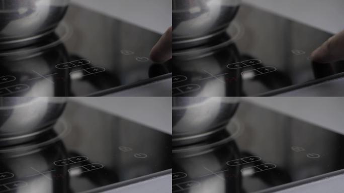男人按了电炉上的一个按钮。一只男性手包括一个感应炉。现代技术。电饭煲的触摸面板。电影4k视频
