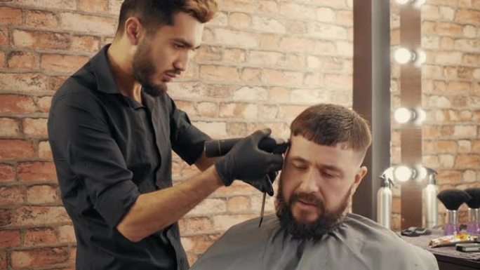 年轻的理发师在理发店为英俊的男顾客理发