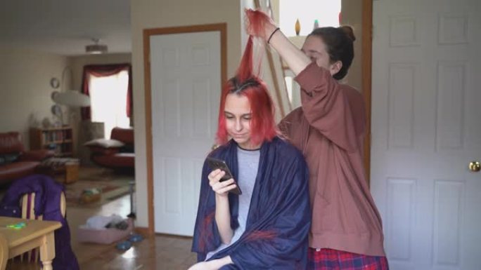 姐姐在家里剪了妹妹的头发，而她正在与朋友视频聊天，并在网上直播理发的过程。