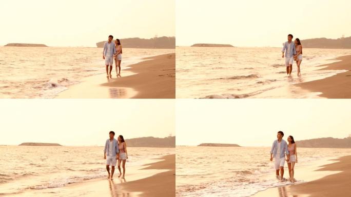 快乐的亚洲年轻夫妇在日落时在沙滩上散步