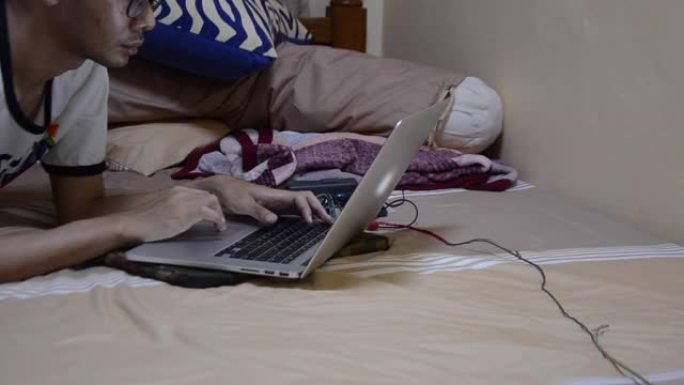 男子躺下，开始在床上的笔记本电脑上工作。