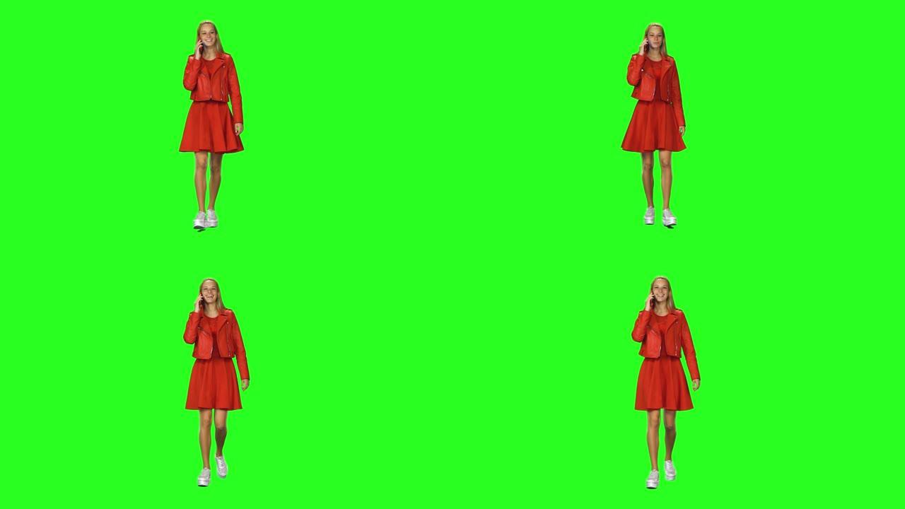 金发女孩在绿屏背景下平静地在手机上行走和交谈。色度键。前视图