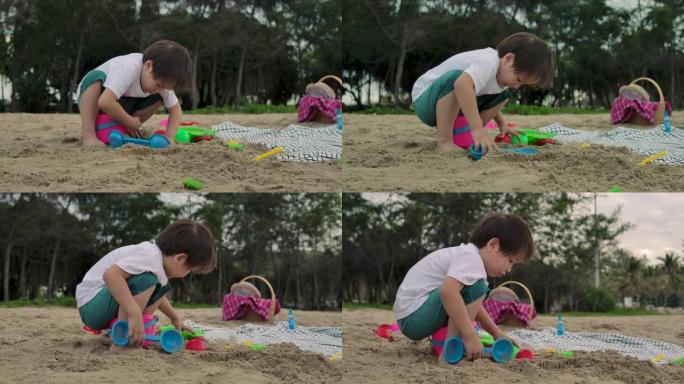 度假的男孩在海滩上玩耍，堆起一堆沙子。