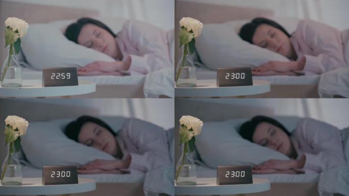 时钟和玫瑰的选择性焦点在晚上睡在床上的女人附近的桌子上
