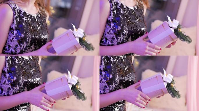 女性手中的粉色礼品盒。红色修指甲的女性手拿着白色蝴蝶结的粉色礼品盒。