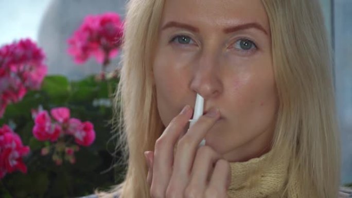 一名妇女在家中使用鼻腔喷雾剂治疗对花卉和植物的花粉过敏。