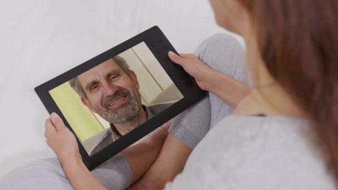 年轻的成年女性女儿在笔记本电脑屏幕上打电话给年长的父亲。女人通过网络摄像头说话。视频电话，家庭聊天概
