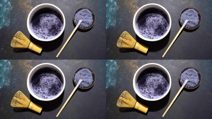 4k视频。碗中蓝抹茶，蓝色抹茶粉和蓝色表面的竹制茶。