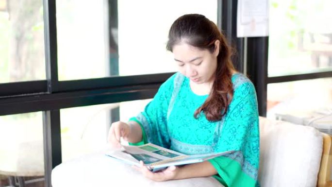 亚洲女人在咖啡店看书。模拟阅读概念