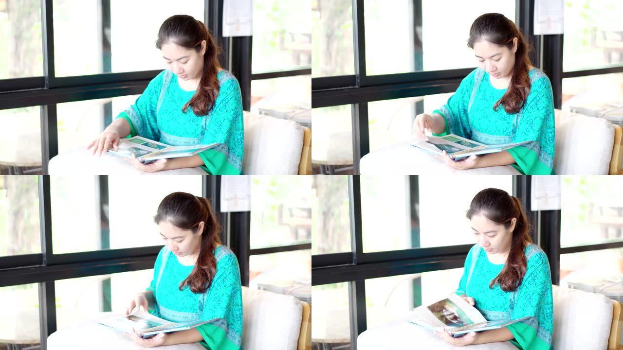 亚洲女人在咖啡店看书。模拟阅读概念