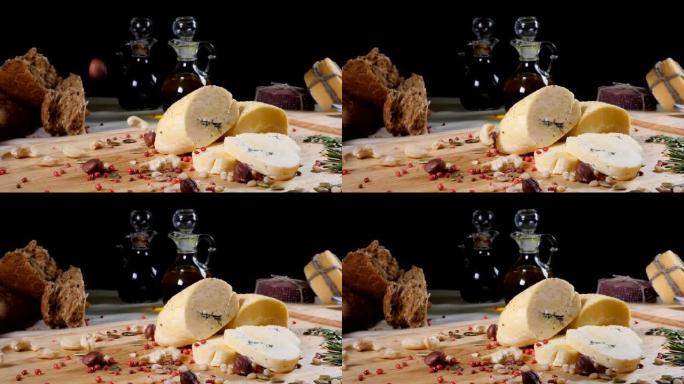 餐厅概念。表设置。切成薄片的硬质奶酪放在木制背景上，带有自制的面包，坚果和橄榄瓶。坚果掉下来。慢动作
