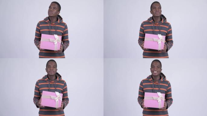 快乐年轻英俊的非洲男人与礼品盒思考
