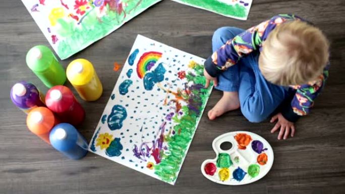 可爱的蹒跚学步的金发孩子，男孩，用颜色绘画，在纸上制作指纹