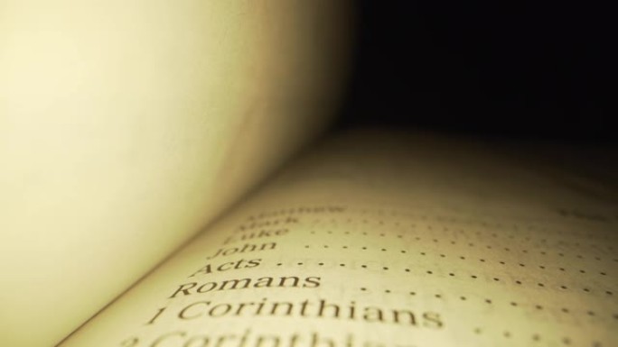 极端微距特写移动滑块拍摄的圣经新约索引书在国王詹姆斯翻译与红色字母的上帝的话在一个黑暗的背景与独特的
