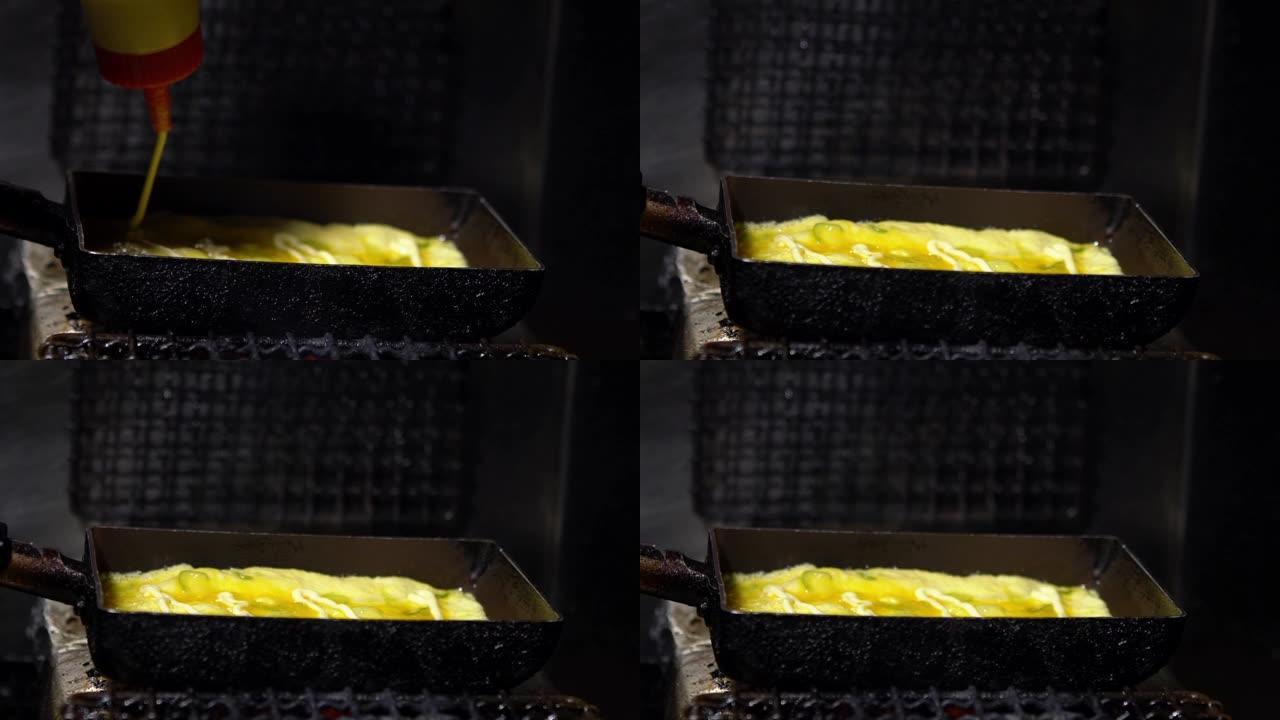 在街头食品市场的金属锅中，tamagoyaki煎蛋卷的慢动作