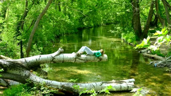 年轻女子在河上方的树林中休息