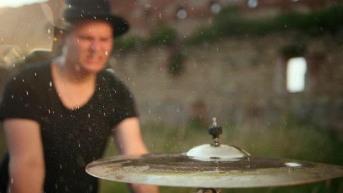 鼓手音乐家在慢动作中敲打湿鼓钹和水溅