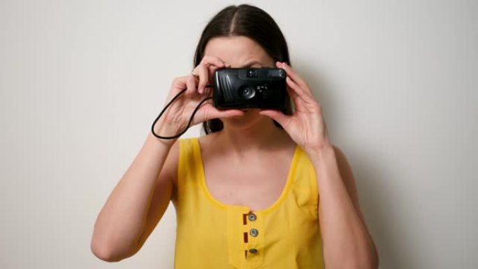 穿着黄色t恤的女摄影师在旧的塑料相机上拍摄肥皂碟