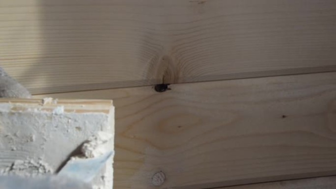 工人把油灰放在木墙的一个洞里