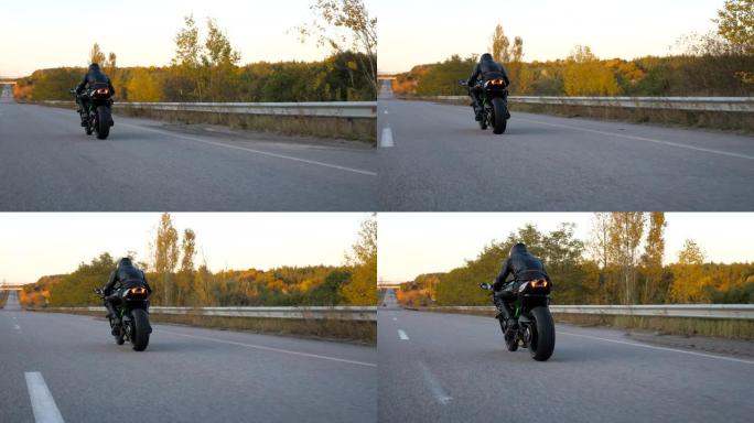 无法识别的戴头盔的人在高速公路上快速骑现代运动摩托车。摩托车手在乡间小路上骑摩托车。旅途中开车的人。