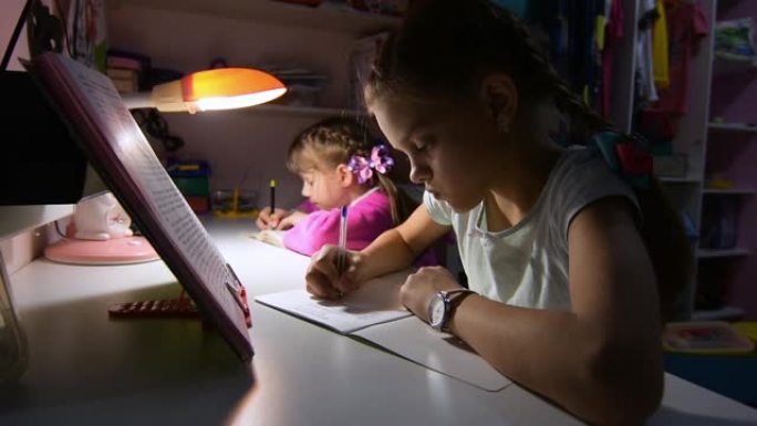 两个女孩深夜在台灯的灯光下做作业