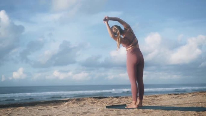 站在海洋海滩上的苗条女人做半月形瑜伽姿势