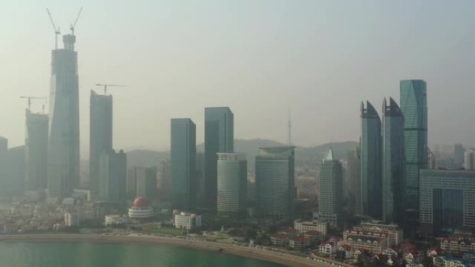 阳光明媚的夜晚青岛市市中心摩天大楼建设海湾空中全景4k中国