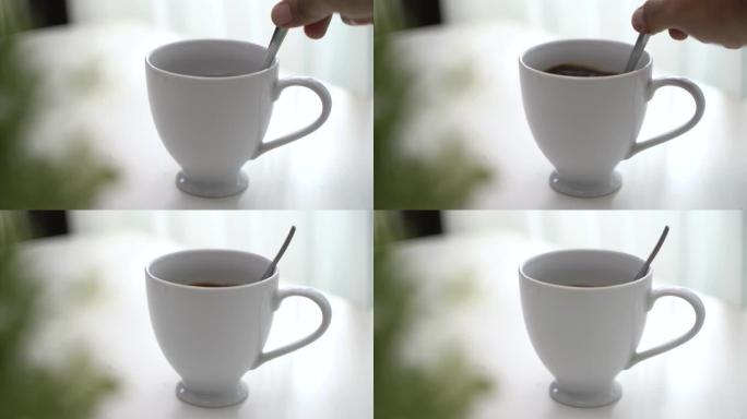 男性用勺子在白色咖啡杯中搅拌咖啡的俯视图和特写镜头。4k分辨率。