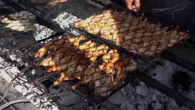 烹饪海鲜的特写镜头。在烧烤架上烤腌虾。巴厘岛4K金巴兰食品市场出售的巨型淡水虾木炭烧烤