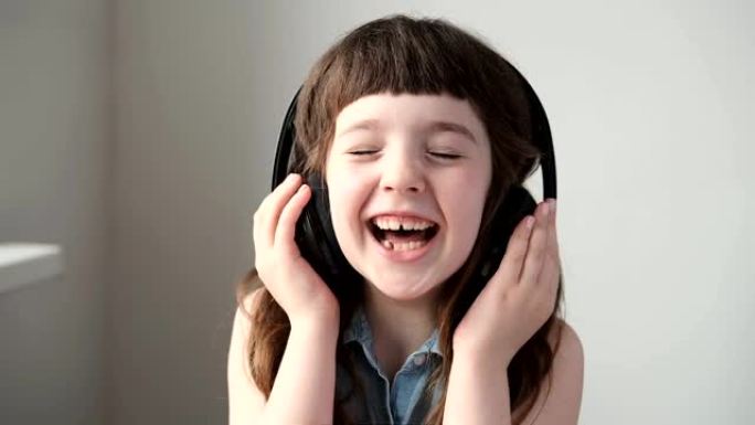 戴大型无线耳机的女孩听着笑。特写。