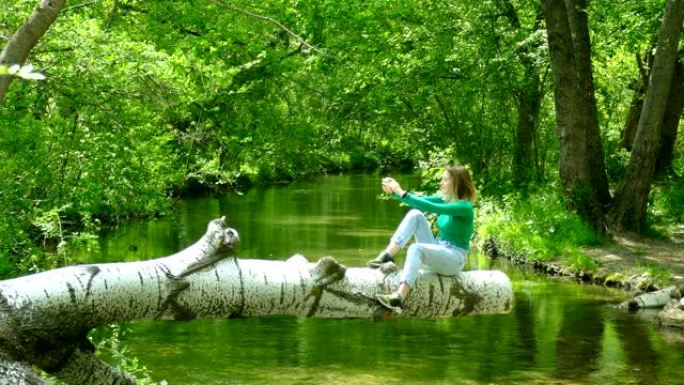 年轻女子在森林河上拍摄自然