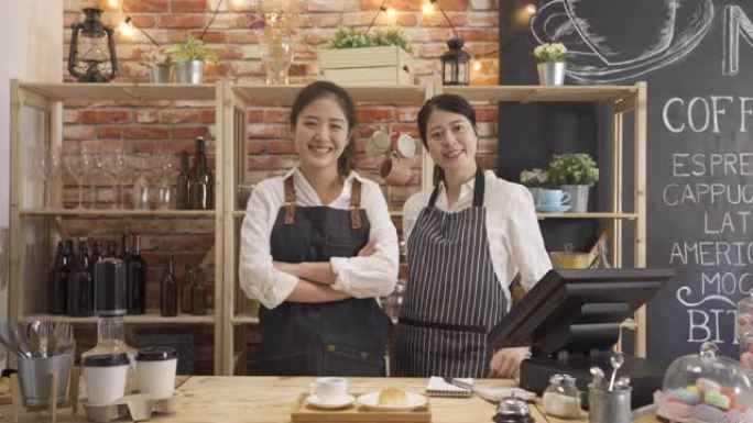 两个最好的朋友合作自己的小型创业公司咖啡店。穿着围裙的年轻女孩咖啡师站在库特纳面对镜头，微笑着快乐可