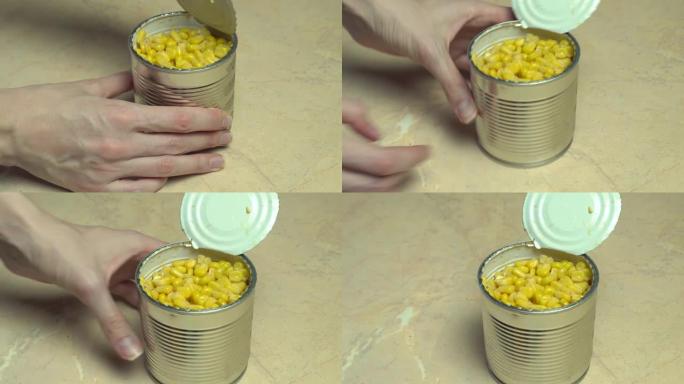 一只雌性的手打开一个罐装玉米的铁罐。