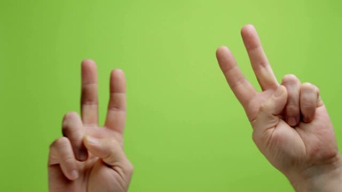 手是符号。男人的手在绿色背景上显示出和平与胜利的姿态