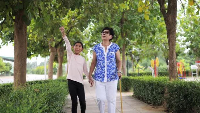 亚洲高级妇女在公园里散步，她的孙子，生活方式理念